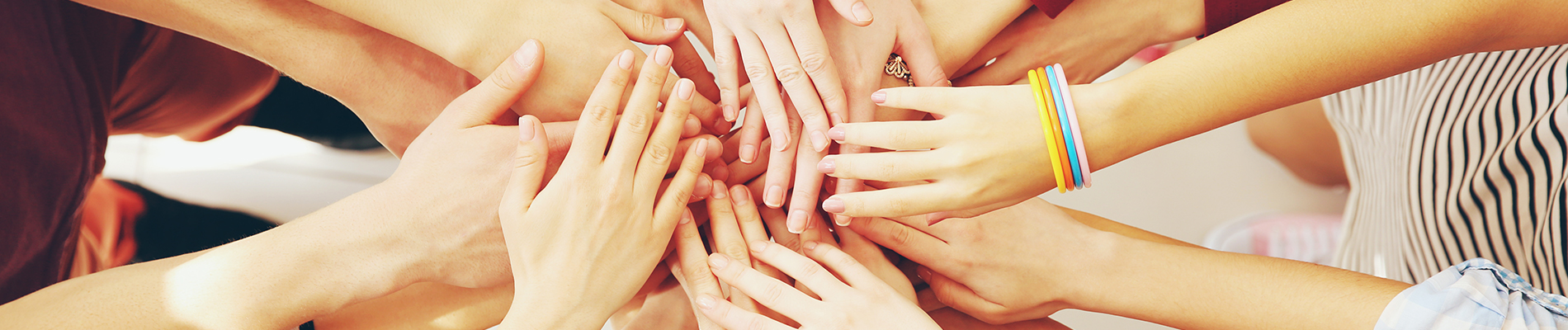 The image shows a group of people with their hands joined together in a circle, creating a sense of unity and camaraderie.