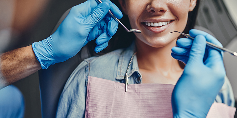 A dental hygienist performing a cleaning procedure on a patient s teeth.